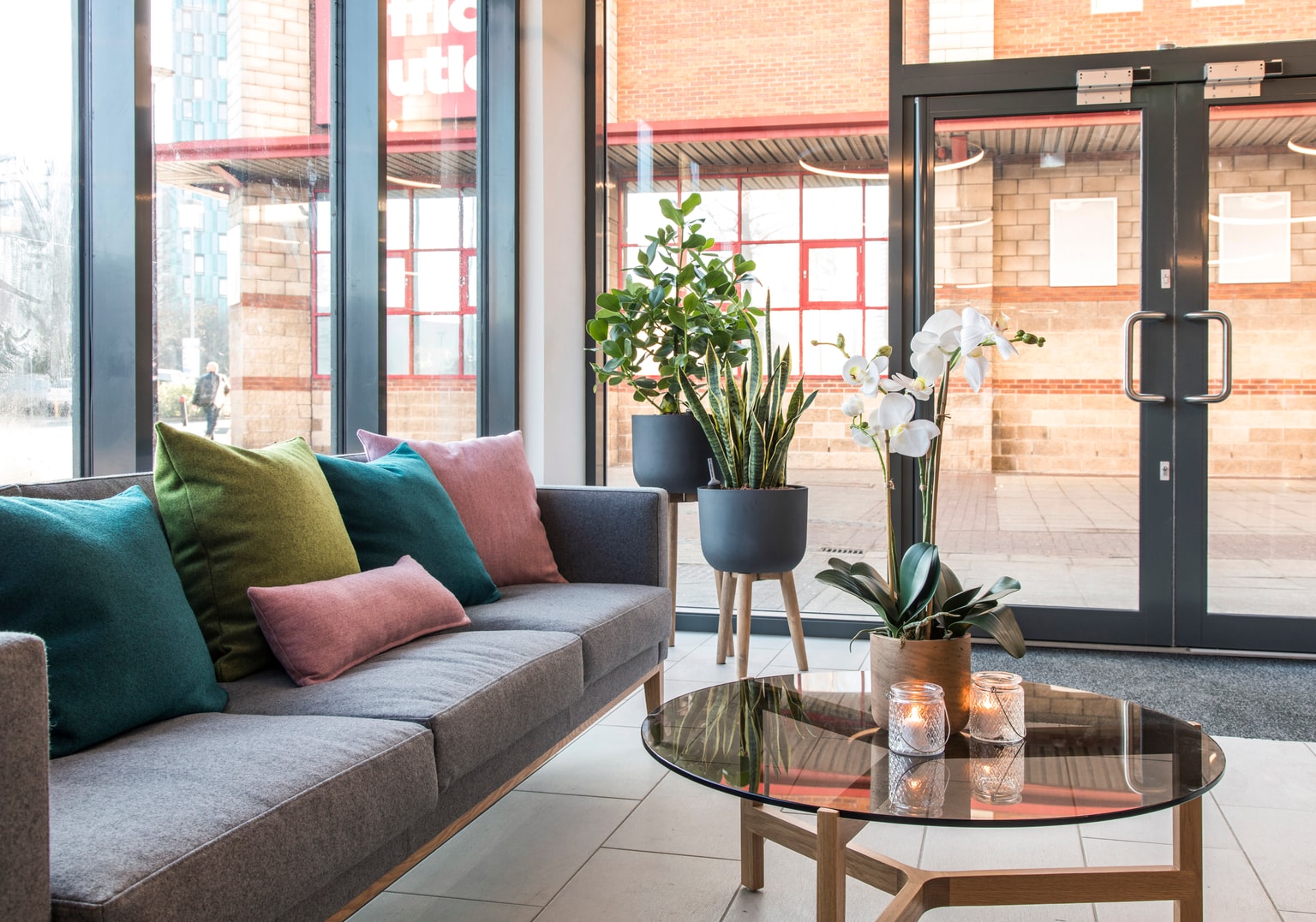 Image of Reception area with grey sofa, plant pots and coffee table on display