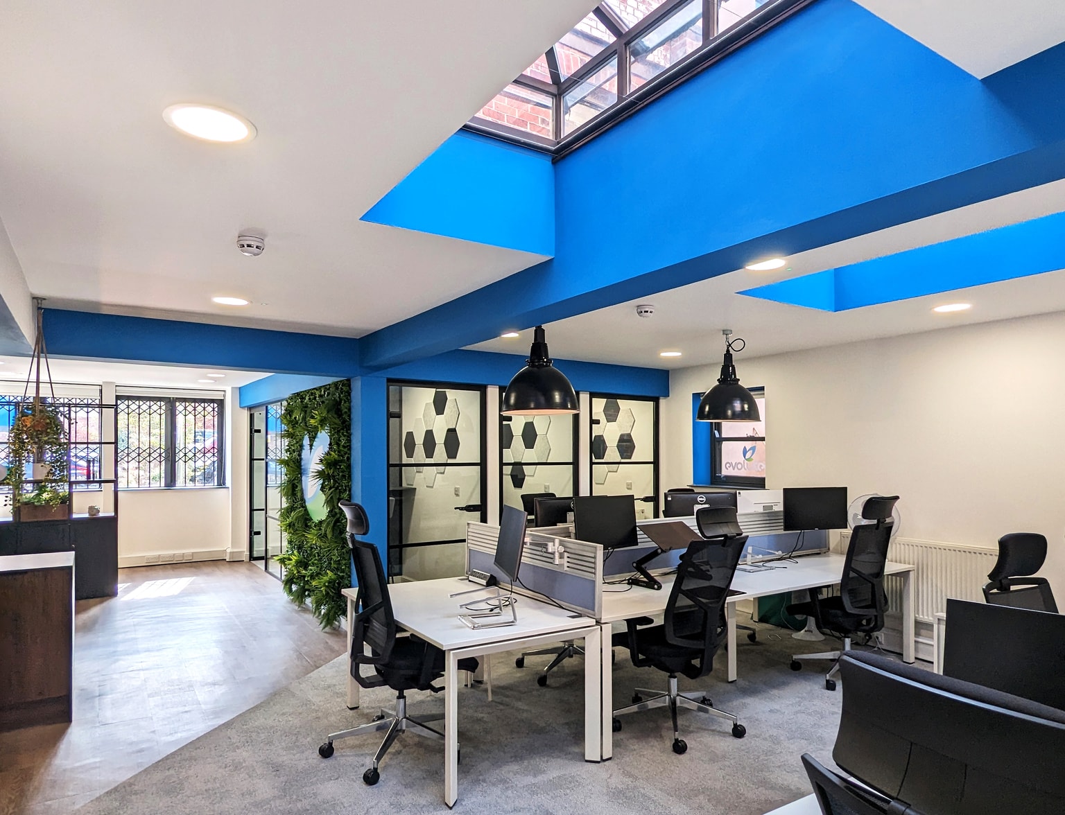 Image of shared desk space with meeting rooms visible in the background