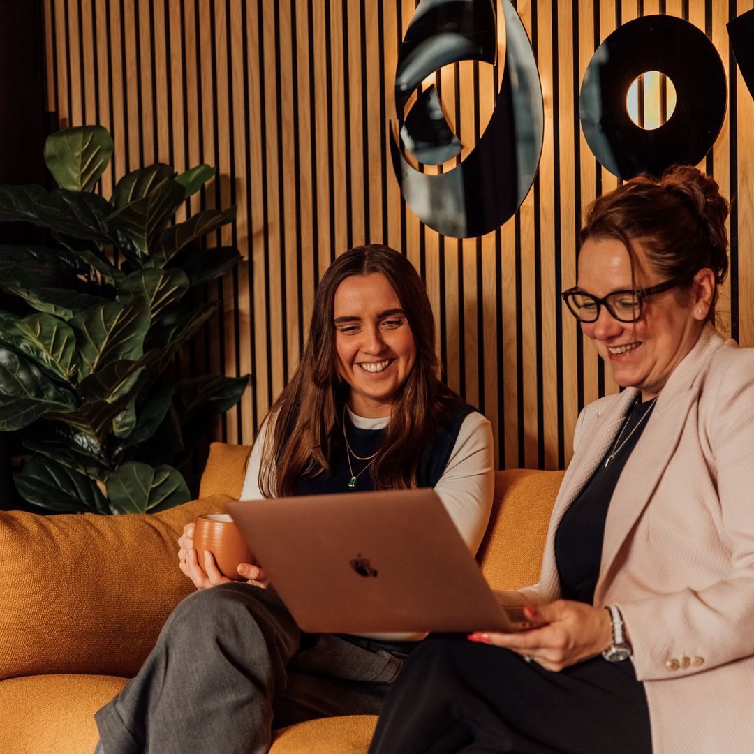 Image of colleagues discussing work over a laptop